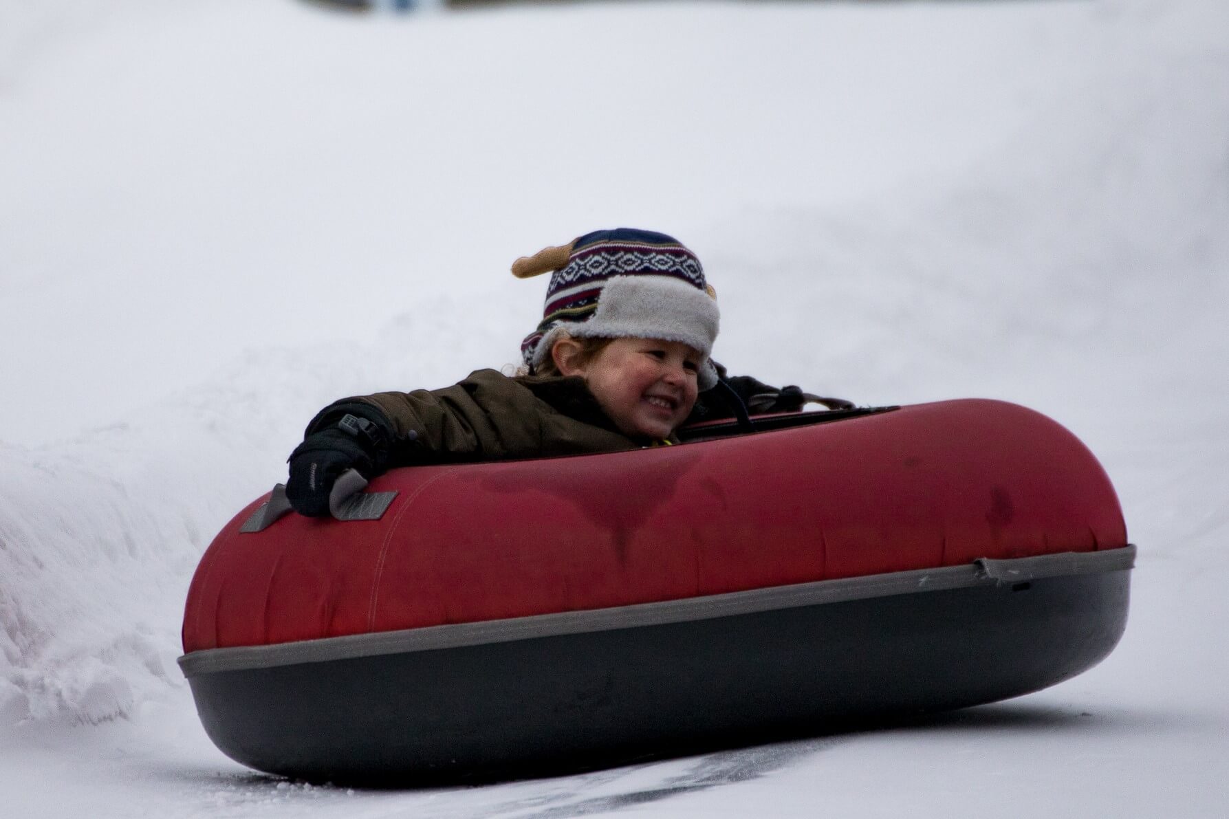 A child tubing down a hill and enjoying a Family Vacation in Vermont.